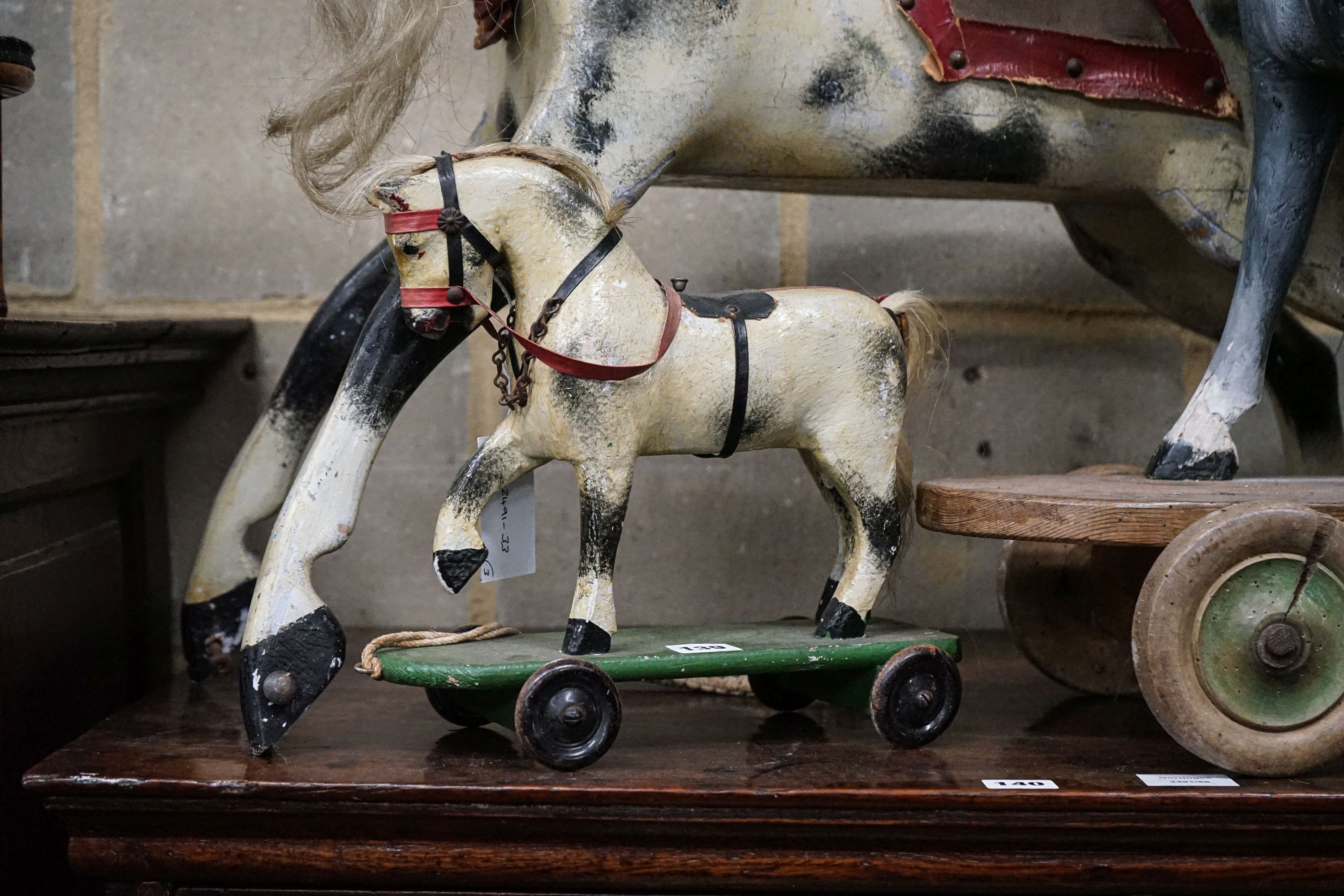 A Victorian carved and painted wood rocking horse, lacking underframe, length 77cm and two painted wood hobby horses, 58cm and 38cm